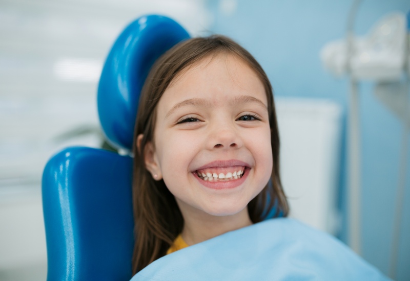 A child sitting in a dental chair is happy after receiving pediatric dentistry treatment in Parker